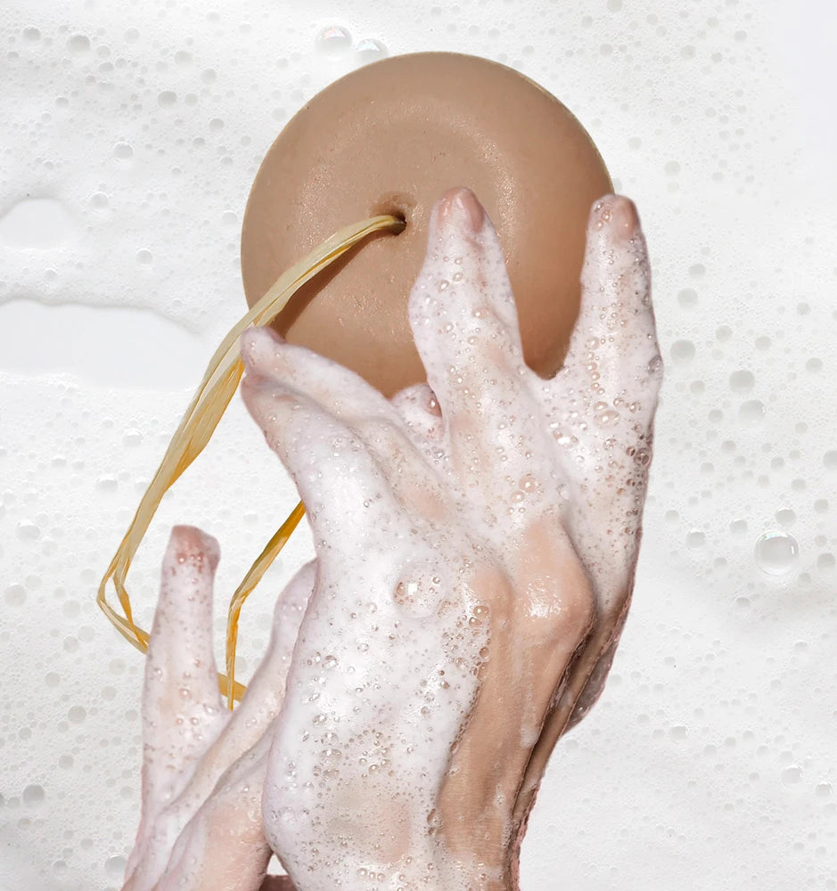 Shampoo naturale con ingredienti liquirizia, argilla bianca e olio di vinaccioli accanto a capelli voluminosi e sani